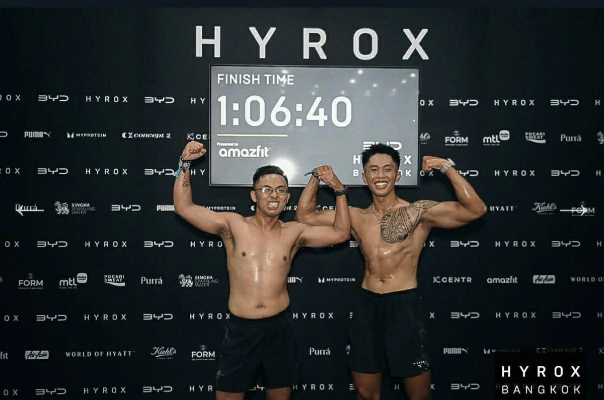 Long Vũ and his partner flexing under the 1:06:40 HYROX Bangkok Doubles Pro finish clock