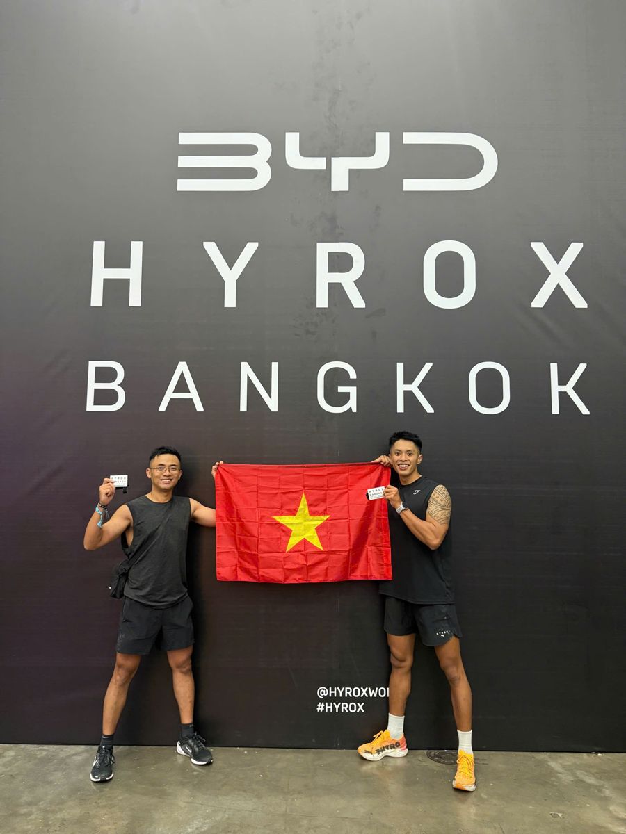 Long Vũ and his partner holding the Vietnamese flag at HYROX Bangkok